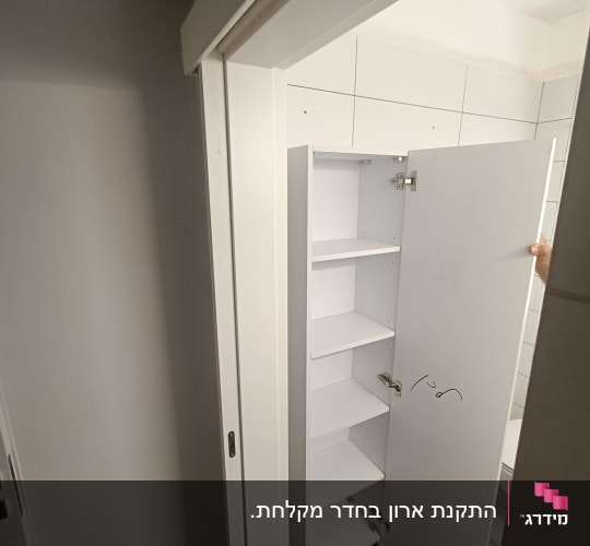 ארון לבן עם דלת פתוחה בחדר אמבטיה